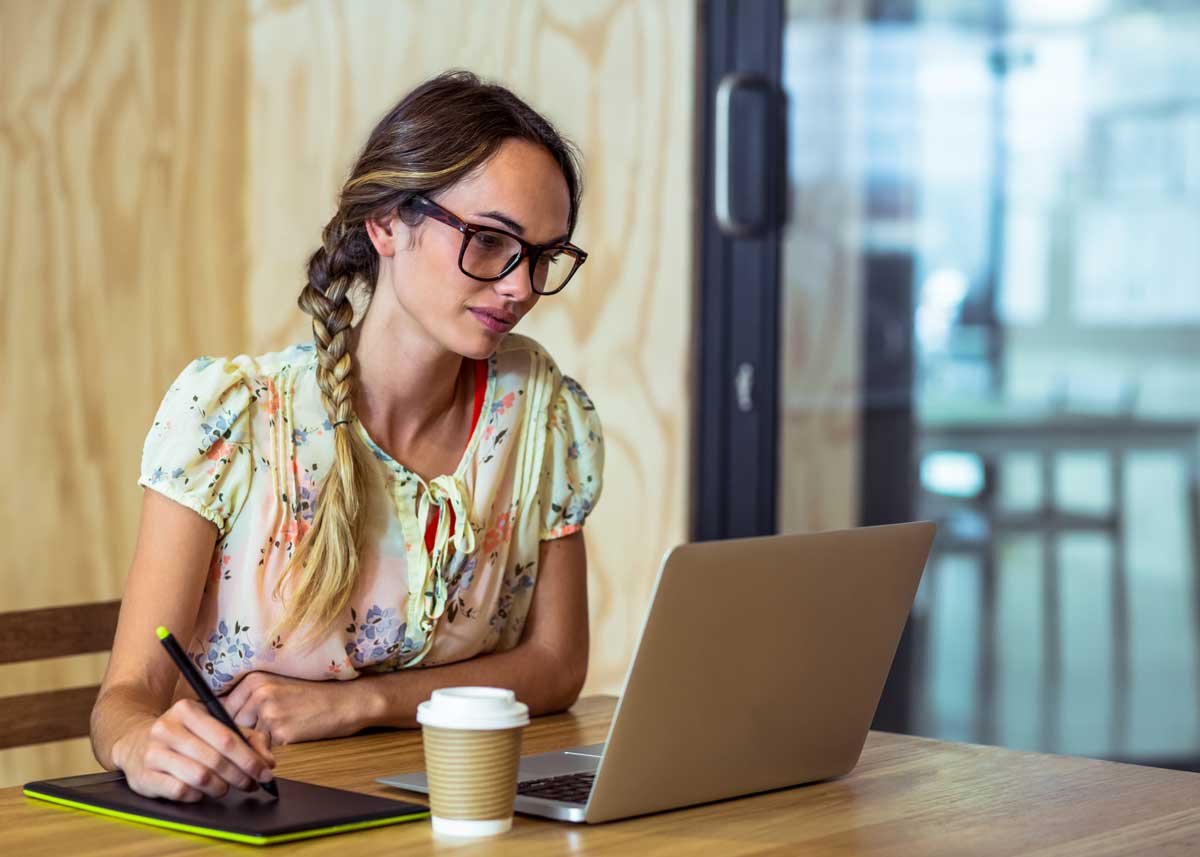 A female  graphic designer sits working at a computer.