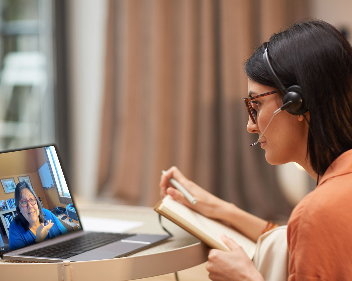 An image of a woman watching a laptop screen on which Andrea Hill is making a presentation